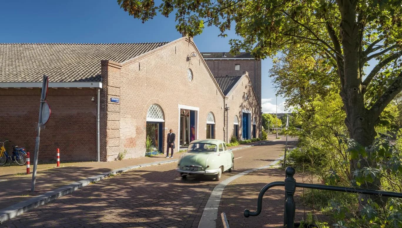 A oldtimer car driving over a sunny Entrepotdok during early autumn.