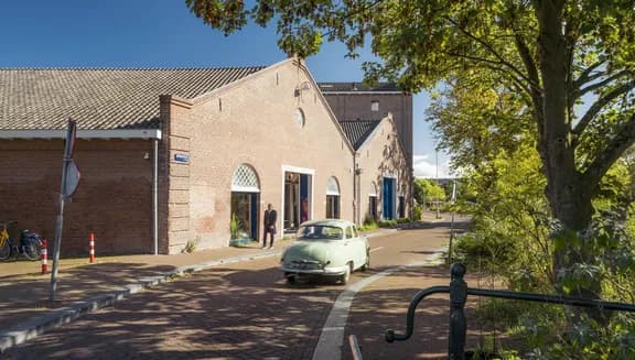 A oldtimer car driving over a sunny Entrepotdok during early autumn.
