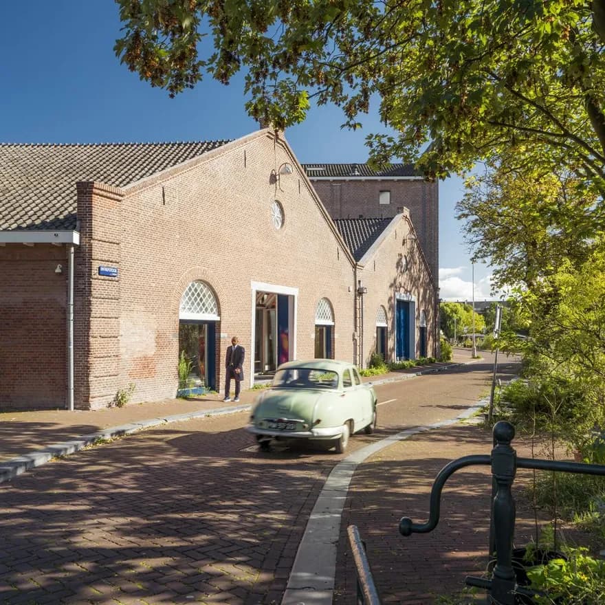 A oldtimer car driving over a sunny Entrepotdok during early autumn.