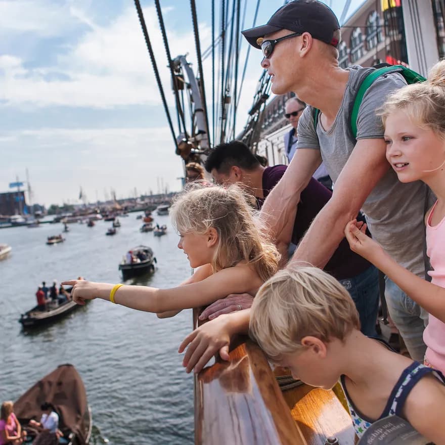 Bezoekers op de Christian Radich kijken naar de voorbijgaande bootjes.