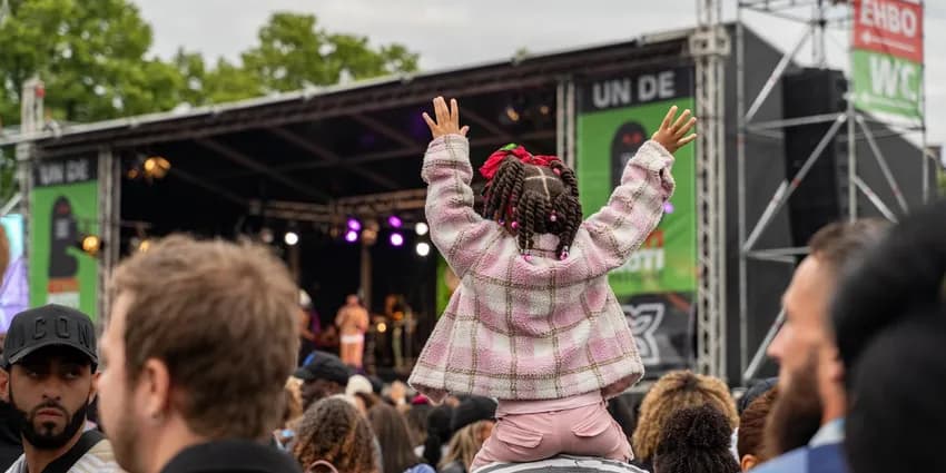 A little girl sitting on her dads shoulders during Keti Koti 2023 at Museumplein.