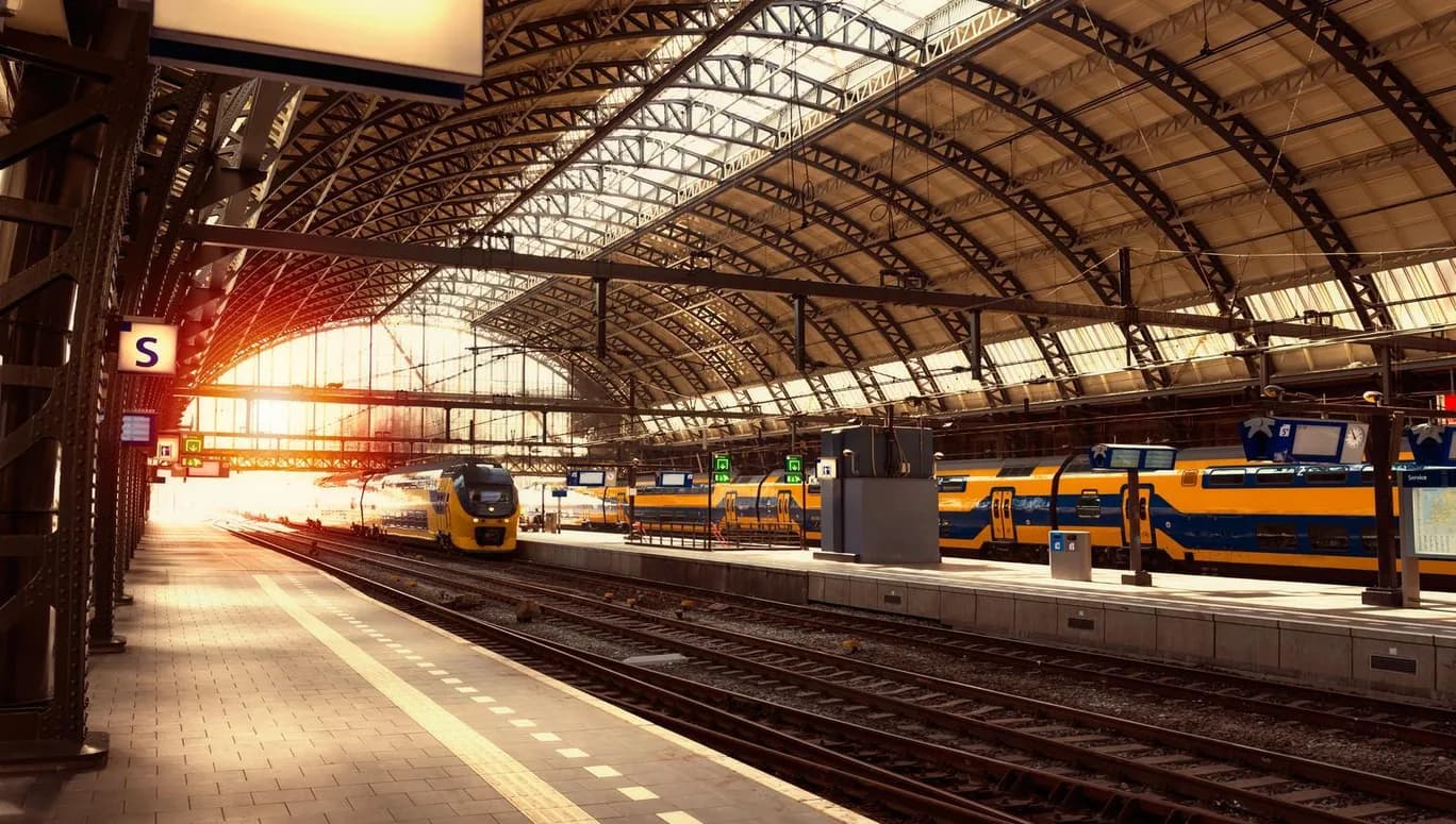 Platform of Amsterdam Central Station, with NS trains on the railways behind.