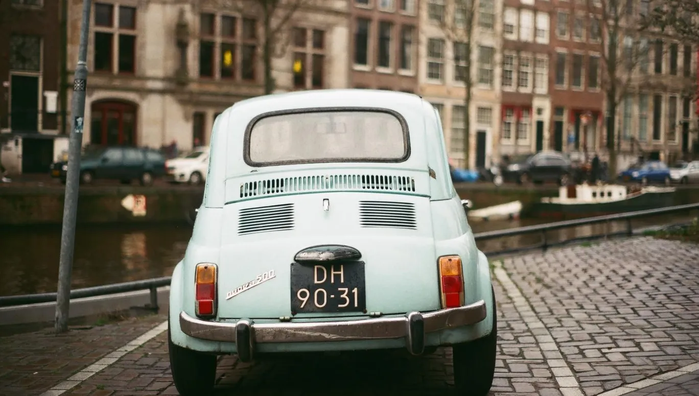 Blue vintage Fiat car parked by the canal.