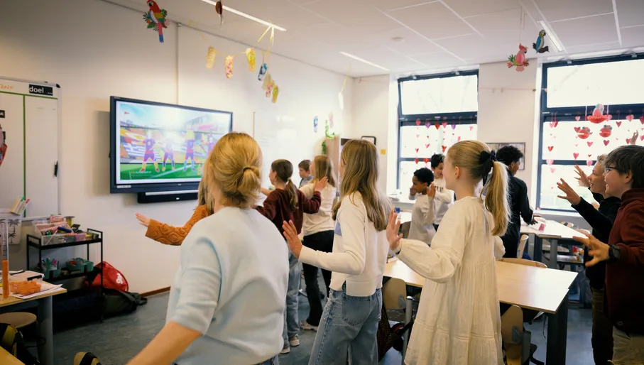 Students follow along to an interactive lesson in a classroom.