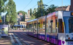 Colourful tram with Pride flag arriving at Javaplein.