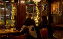 People sitting inside brown bar 't Hooischip by night