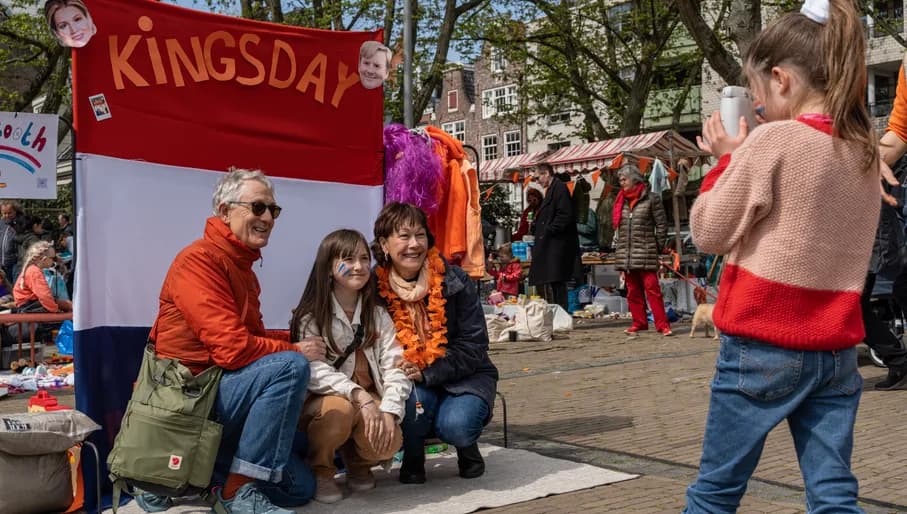 A family posing for a picture on the Amstelveld flea market on King's Day 2023.