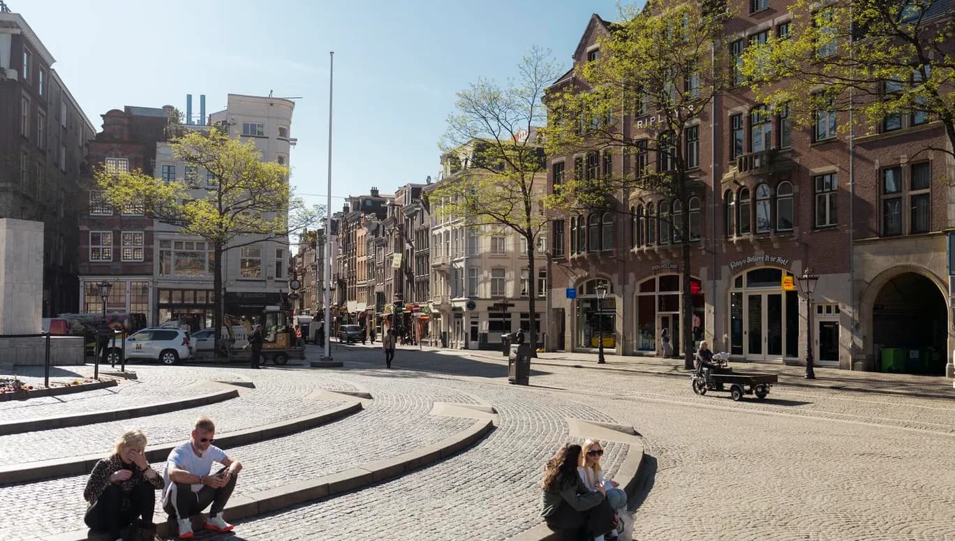 People enjoy the sun on Dam Square.