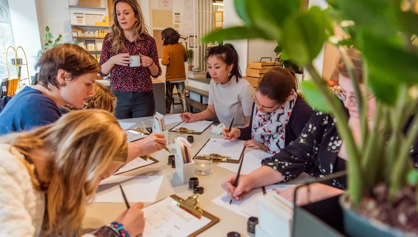 People taking a Calligraphy workshop writing on a clipboard paper holder