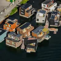 De dertien waterwoningen zijn door zes verschillende ontwerp partijen ontworpen, wat een divers aanzicht geeft. Allemaal hebben ze een betonnen drijflichaam en een opbouw van houtskeletbouw. Er zijn circa 500 zonnepanelen geïnstalleerd op de daken en douchen en afwassen gebeurt als het kan met opgevangen regenwater in een spaardouche. Het particulier opdrachtgeverschap Schoonschip bouwde samen met Bouwbedrijf van Middendorp deze drijvende wijk die in 2019 is opgeleverd. Foto John Gundlach.