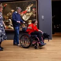 Happy woman in a wheelchair and a dog, visiting Rijksmuseum