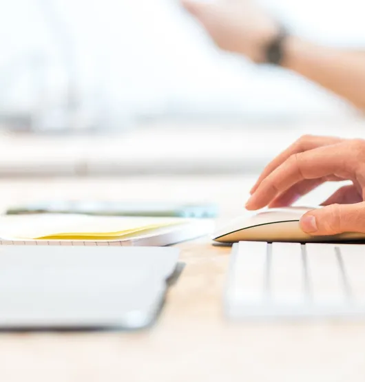 Close up of hand moving mouse next to laptop on desk.