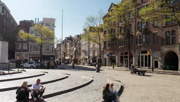 People enjoy the sun on Dam Square.