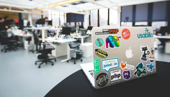 Laptop with Startup Amsterdam sticker and other stickers on desk in office