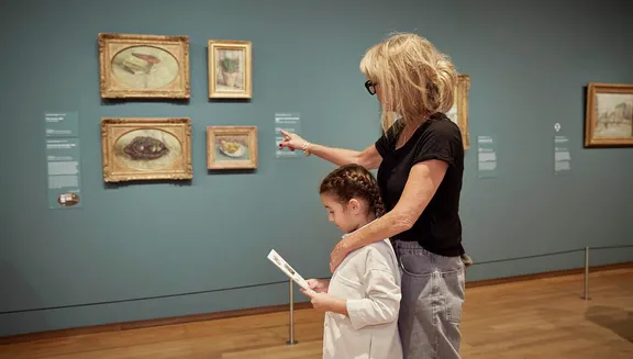 An adult and a girl are visiting Van Gogh Museum.