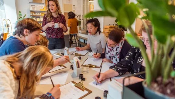 People taking a Calligraphy workshop writing on a clipboard paper holder