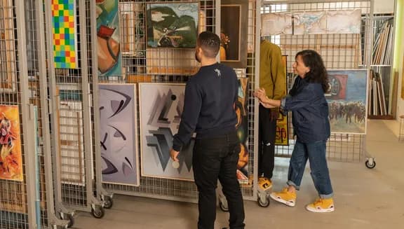 A man looks at the art that is being shown to him by the employe at the art loan of CBK Zuidoost.