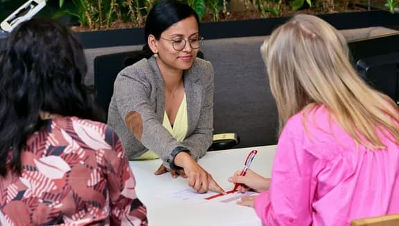 Two women sitting at the desk at the INAmsterdam offices, employee pointing out where to sign the papers