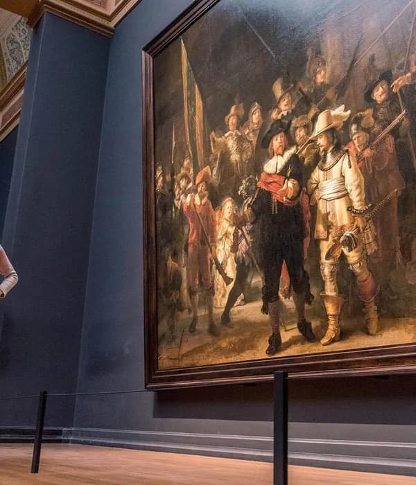 Three women gathered around Rembrandt's Nachtwacht (Nightwatch) painting in the Rijksmuseum.