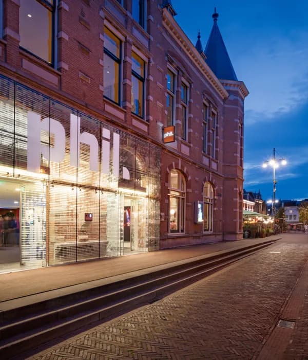 Couple walking past the exterior of PHIL Haarlem concert hall at night
