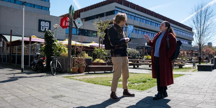 Man and woman having a conversation on the sidewalk of Wibautstraat.