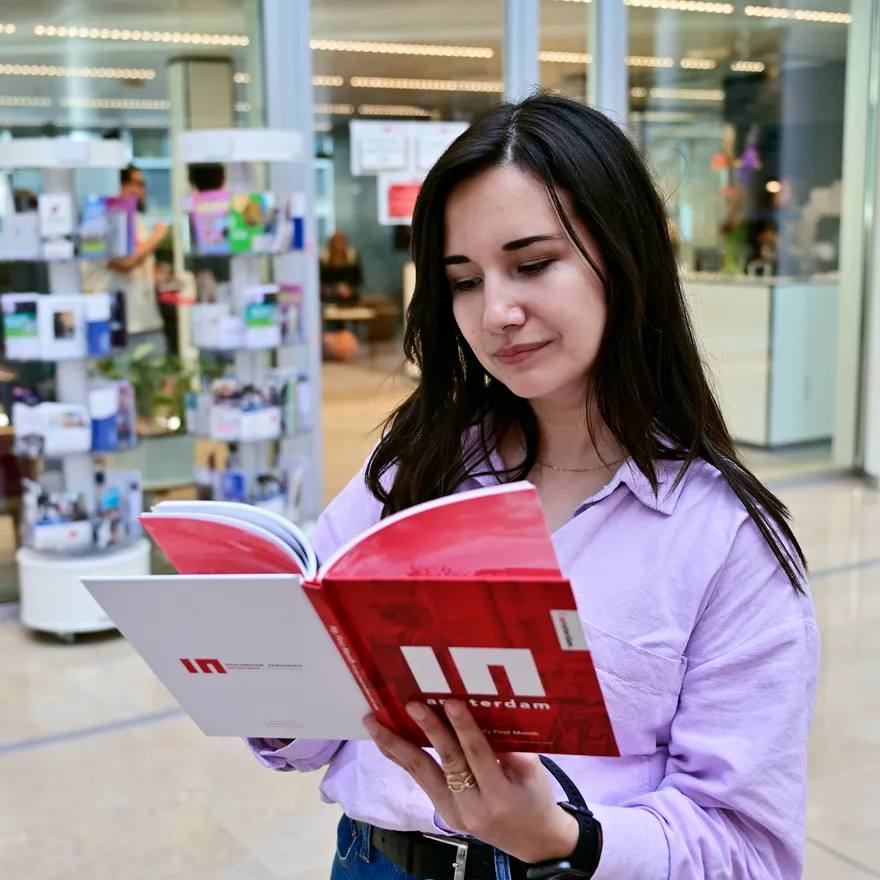 Woman reading INAmsterdam booklet in front of INAmsterdam offices