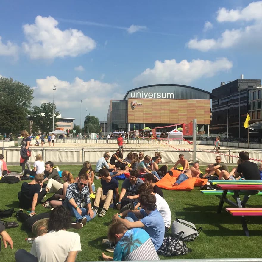 Students sitting on the grass in summer in front of University building of Physics UvA