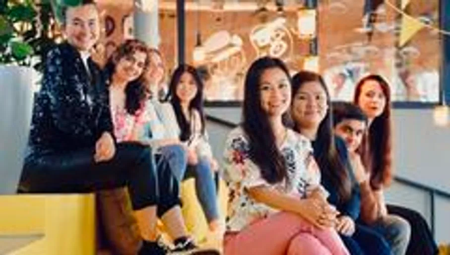 Minite group sitting indoors on benches.