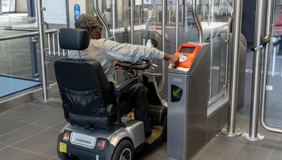 A person in an electric wheelchair checking out in order to exit metro station Noord.