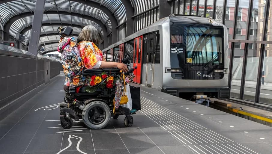 A person in an electric wheelchair waiting for the metro.