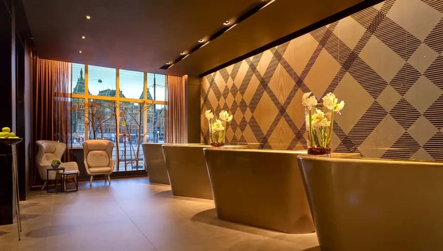 Interior of lobby of Park Plaza Victoria hotel in Amsterdam, with Central Station visible through window in the background.