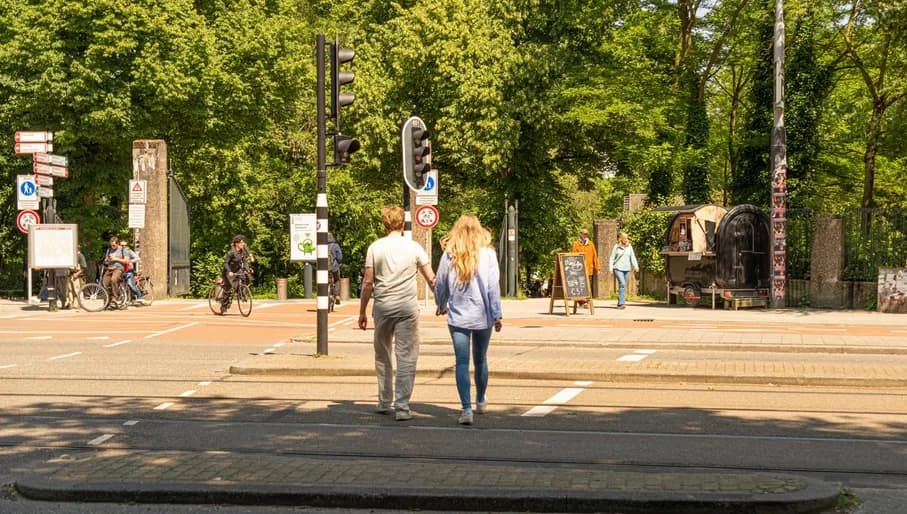 Couple holding hands and crossing road into Vondelpark