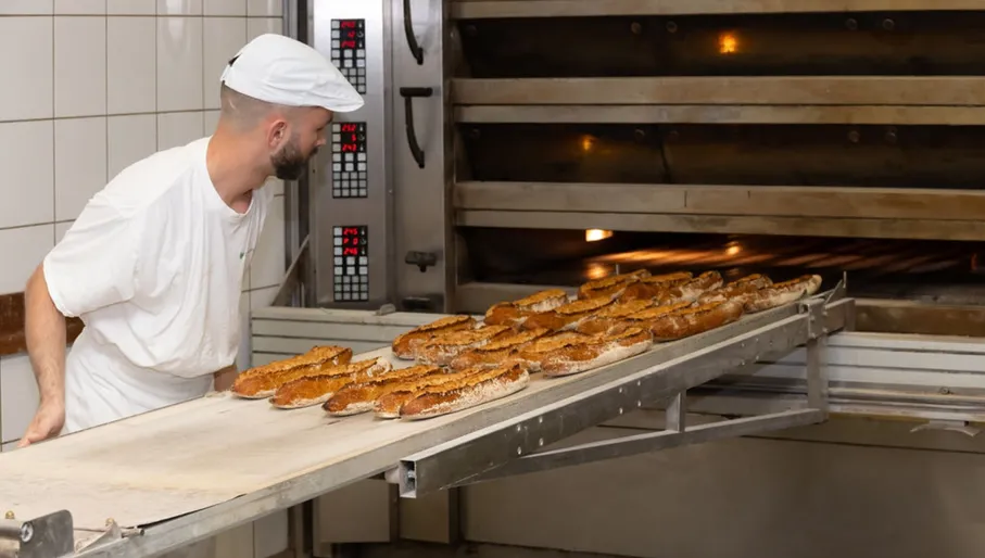 Le Fournil de Sebastien baker taking out fresh bread from the oven