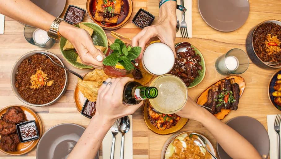 People cheering over dishes at Warna Baru Indonesian restaurant