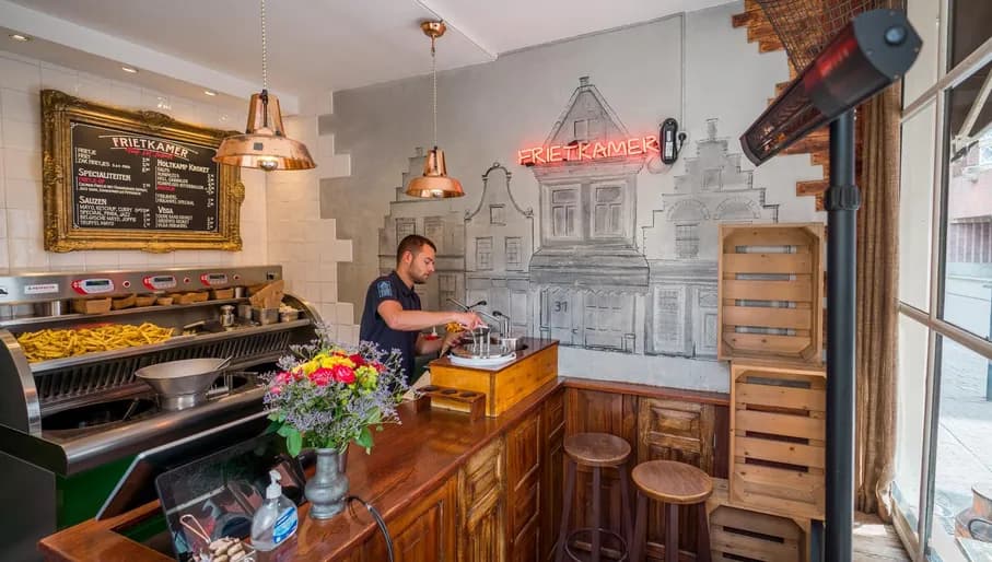 The chef of the Frietkamer sprays sauce over the french fries