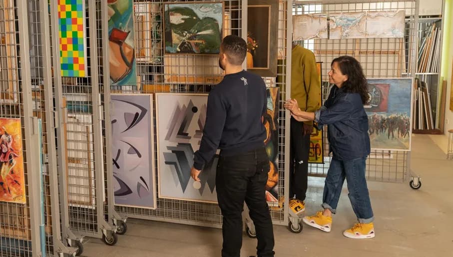 A man looks at the art that is being shown to him by the employe at the art loan of CBK Zuidoost.