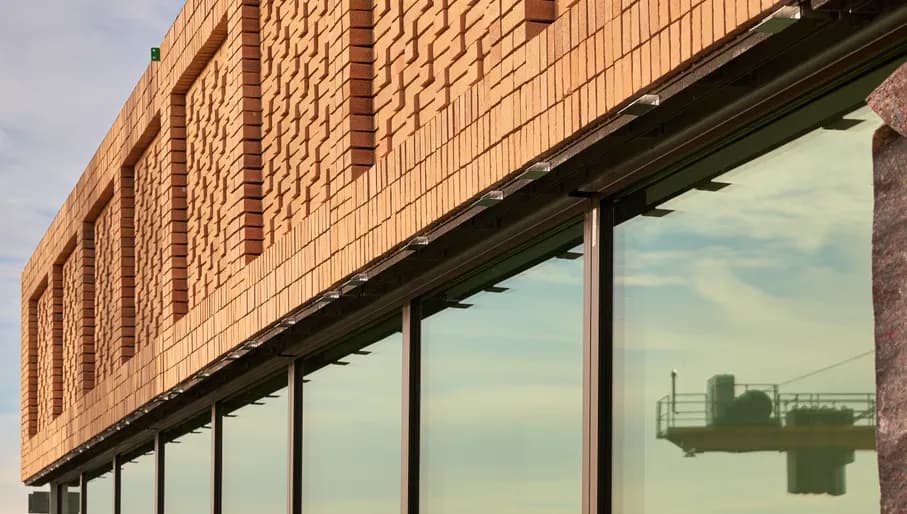 Brick building facade, in the evening sun, with a crane reflection in the window.
