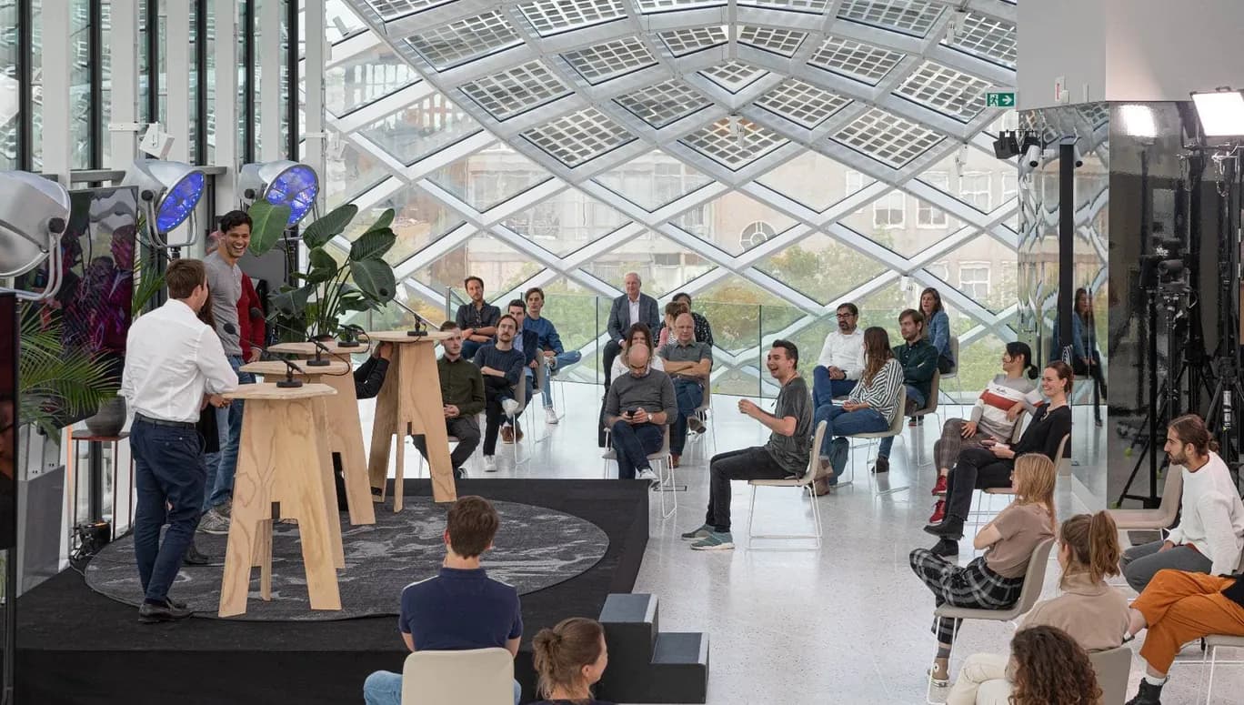 A hybrid event taking place at Capital C hotel in Amsterdam, with a stage and socially distanced audience members.