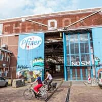 People cycling past IJhallen Pfizer Doors