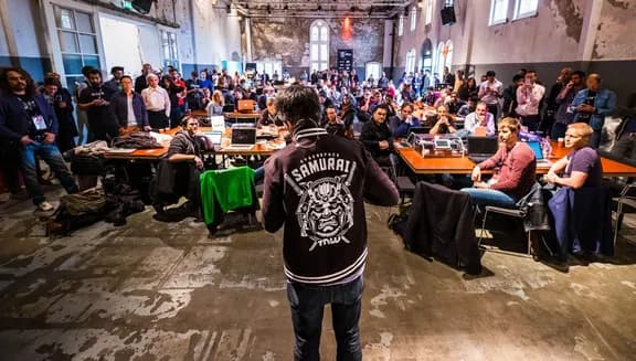 Hack Battle 2016 speaker seen from behind people sitting down.