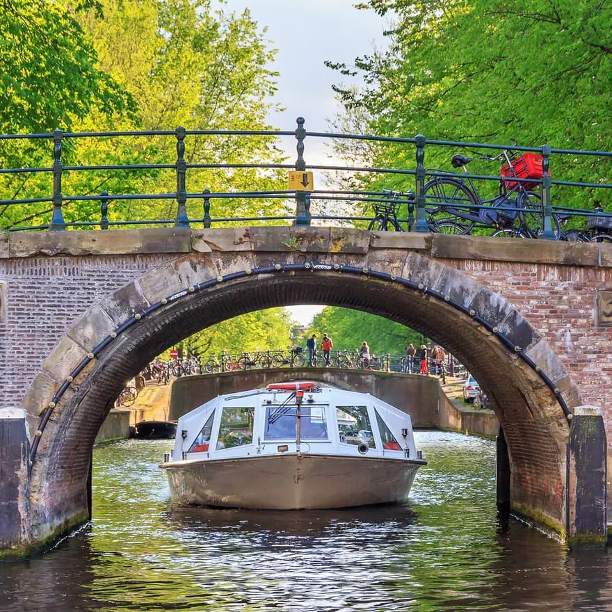 Canal cruise boat goes under the bridge over the Herengracht canal.