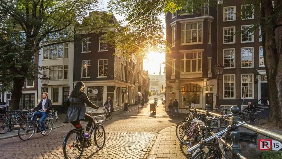 Amsterdam, Netherlands - September 22, 2021: Early morning in Amsterdam. Artistic image. People ride bicycles, the ancient European city of Amsterdam. Sunlight and silhouettes, beautiful downtown houses. Amsterdam, Holland, Netherlands, Europe