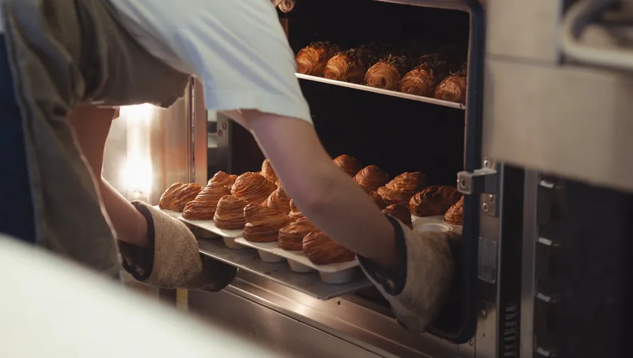 Ulmus bakery baker taking out croissants from the oven