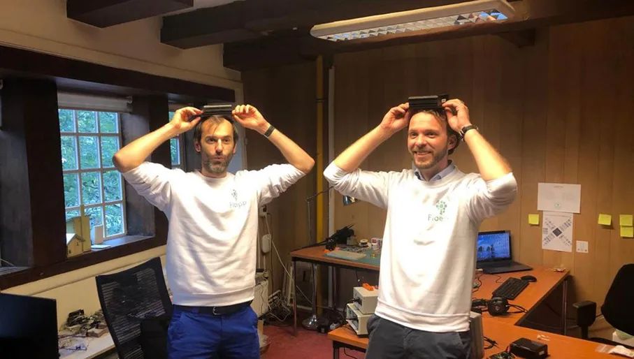 Floepp co-founders Jurriaan Vollebregt and Peter Bontenbal wearing Floepp sweaters holding Floepp sensors over their heads.